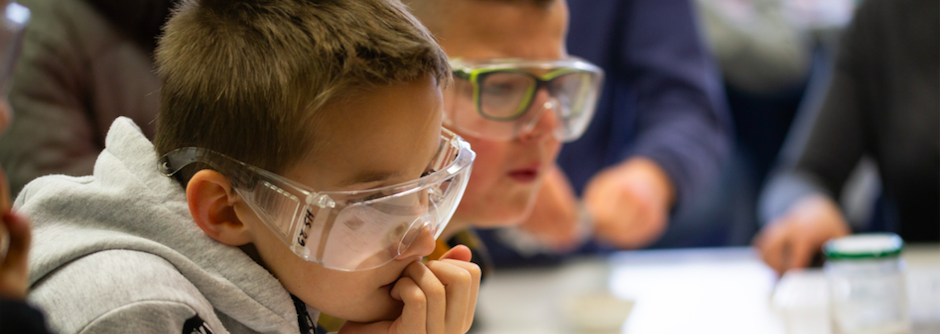 Zwei Schüler mit Schutzbrillen beobachten konzentriert ein Experiment