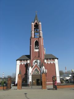 Rote Backsteinkirche mit Glockenturm in Schelkowo